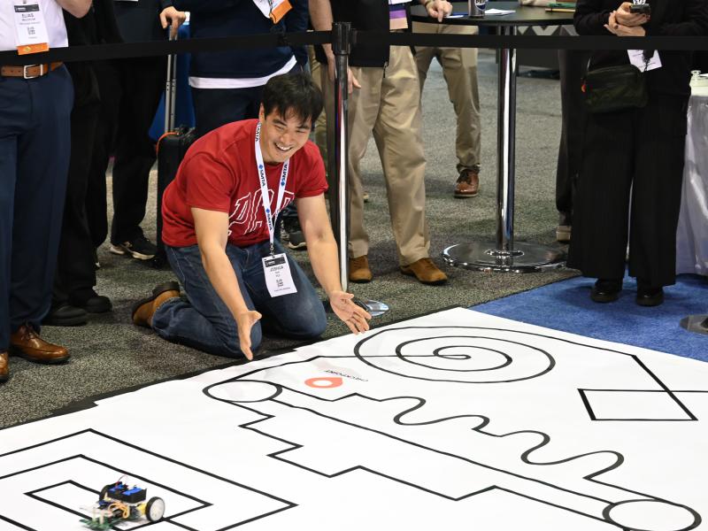 Student smiling watching robotic car on track