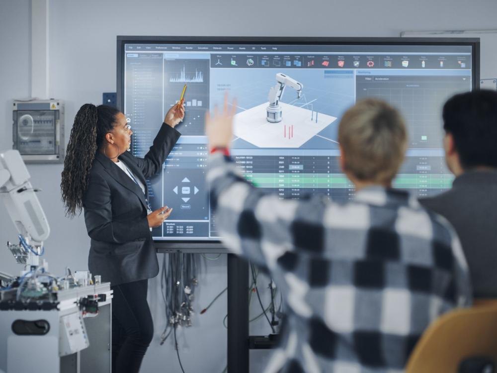 Professor teaching students about robotic arm